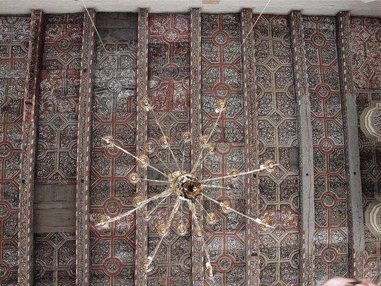 Froschperspektive auf die hölzerne Kassettendecke der Schifferkirche St. Lorenz im Hafen von Lübeck-Travemünde. Nicht nur die quadratischen Paneele, auch die querliegenden Deckenbalken sind mit barocken Ranken in Grisaille und Rostrot bemalt. Für eine Reinigung wurden einzelne Teile gerade herausgenommen. Die Schmuckdecke wurde erst 1990 bei einer Renovierung neu entdeckt und freigelegt. In der Bildmitte hängt ein goldener Kandelaber herab. Die einschiffige Backsteinkirche wurde bis 1621 auf dem Felssteinfundament eines im Stadtbrand 1522 zerstörten gotischen Baus aus dem 13. Jahrhundert errichtet. Sie blieb bis ins späte 19. Jahrhundert eine Filialkirche von St. Marien zu Lübeck